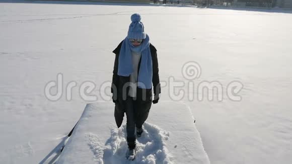 穿着夹克和蓝帽子的女孩在一座白雪覆盖的桥墩上视频的预览图