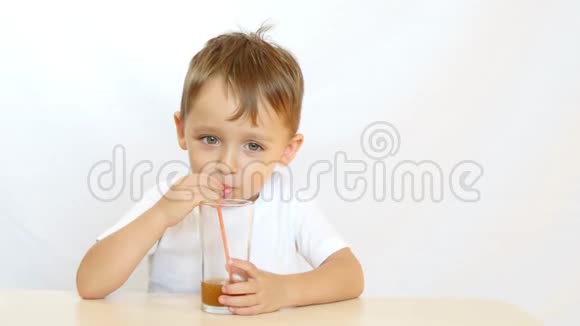 快乐的孩子通过吸管喝果汁坐在桌子旁微笑运动摄像机滑块视频的预览图