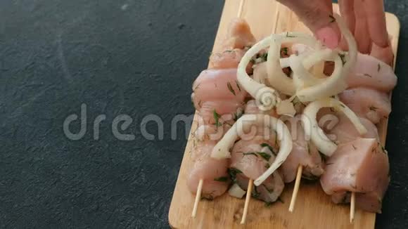 特写女人她的手把洋葱放在腌制的沙什利克从鸡肉上的木串在木板上特写视频的预览图