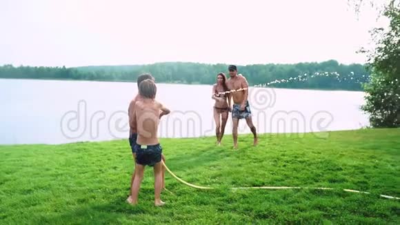 夏日阳光明媚的草坪上一家人带着两个孩子玩得开心玩水笑愉快的气氛视频的预览图
