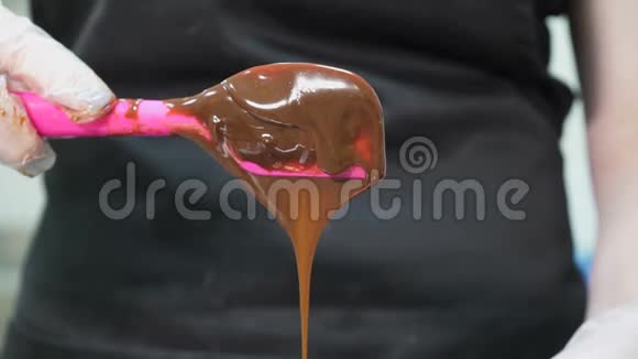 棕色的巧克力从粉红色的糖果勺子里滴出来视频的预览图