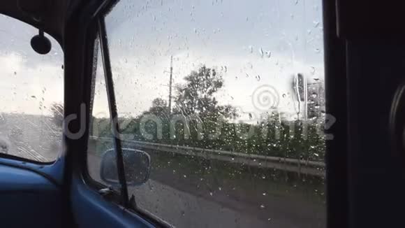 在雨天行驶时通过旧复古车的侧窗观看雨点落在玻璃上视频的预览图