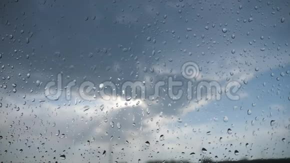 视角透过汽车的挡风玻璃带着雨滴到阴天关闭窗玻璃上的水滴视频的预览图