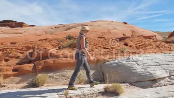 在红岩峡谷的沙漠中行走的徒步女视频的预览图