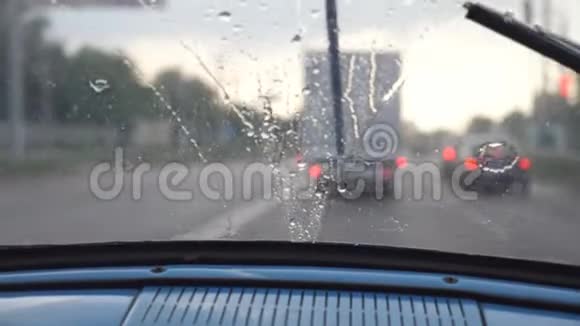 在恶劣天气下从旧复古汽车的前座到挡风玻璃的POV毒蛇将雨滴从窗户中移除视频的预览图