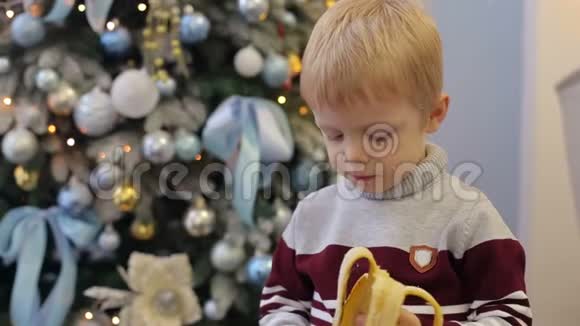 一个小孩子在圣诞树附近吃香蕉视频的预览图