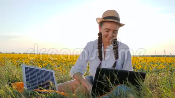 能源生产年轻女性展示手势如在户外使用太阳能电池板女性在背光和笔记本电脑视频的预览图