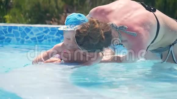 妈妈抱着她的小男孩他在游泳池里玩得很开心视频的预览图