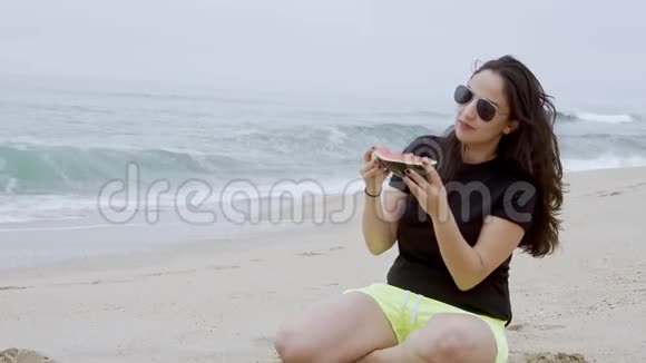 美丽的女人在海滩上吃西瓜视频的预览图