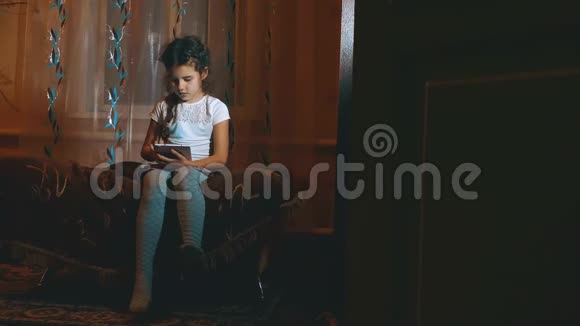 一个可爱的小女孩晚上独自在黑暗的房间里玩平板电脑漂亮的小女孩儿小女孩偷偷玩视频的预览图