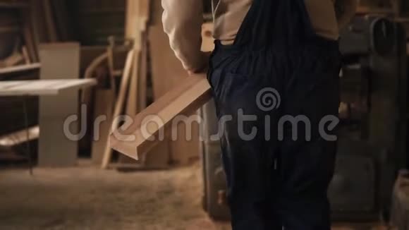 一个男人在木工店工作他走到磨床上在里面安装了一根长钢轨背面视频的预览图