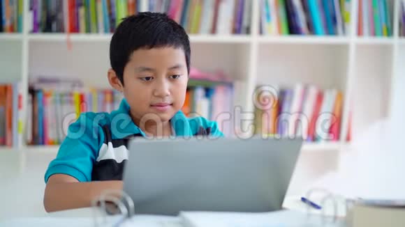 一个带笔记本电脑的男孩在图书馆里微笑视频的预览图
