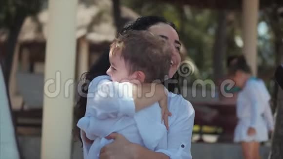 快乐的母亲在海岸拥抱她的孩子可爱的孩子吻他妈妈轻轻拥抱有孩子在户外的概念妈妈视频的预览图