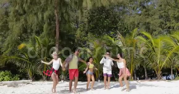快乐的人在北回归线沙滩上举起双手跳舞在度假时将男女同乐视频的预览图