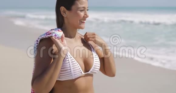 迷人的女人在海滩上调整头发视频的预览图