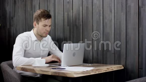 帅哥用笔记本电脑工作商人坐在餐厅的桌子旁拿着他的文件男人坐在咖啡馆里视频的预览图