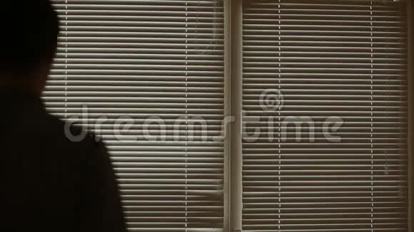 一个人透过百叶窗看着窗外的街道监视着嫌疑犯视频的预览图