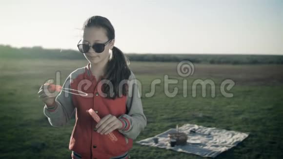 一个戴着太阳镜的漂亮女孩在空旷的草地上吹肥皂泡视频的预览图
