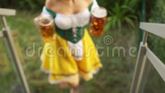 啤酒节女服务员端着两大杯啤酒女孩赤脚走在草地上爬楼梯视频的预览图