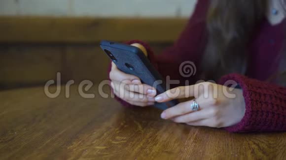 女孩使用智能手机应用程序和微笑在咖啡馆近距离射击年轻的休闲女性专业手机视频的预览图