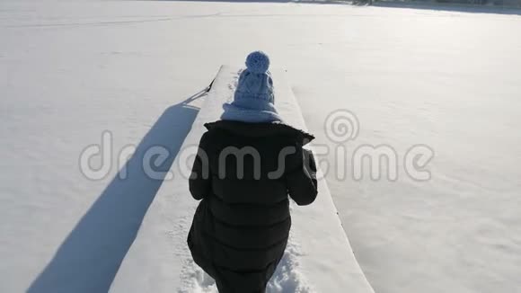 穿着夹克和蓝帽子的女孩在一座白雪覆盖的桥墩上视频的预览图