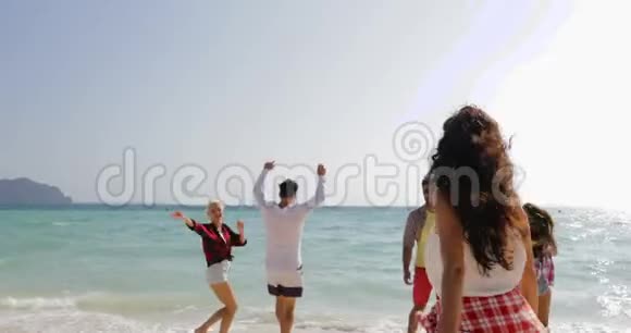 快乐的人在沙滩上奔向水快乐的男女组合跳跃的游客在海上假期的自由视频的预览图