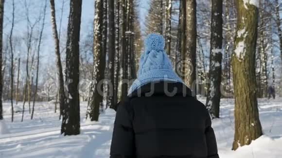 穿着夹克戴着蓝色帽子戴着围巾的女人沿着小巷走视频的预览图