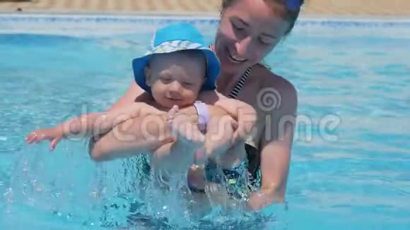 妈妈抱着她的小男孩他在游泳池里玩得很开心视频的预览图