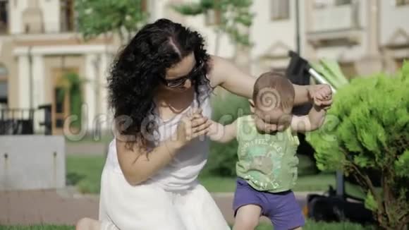 母亲让孩子前臂教孩子迈出第一步宝宝迈出第一步妈妈在玩视频的预览图