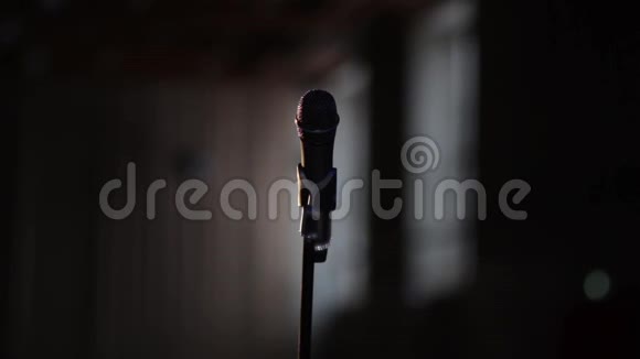 声乐舞台话筒手持话筒站在舞台黑暗背景上视频的预览图