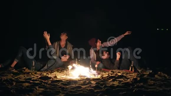 两对可爱的情侣深夜坐在篝火旁看着星星视频的预览图