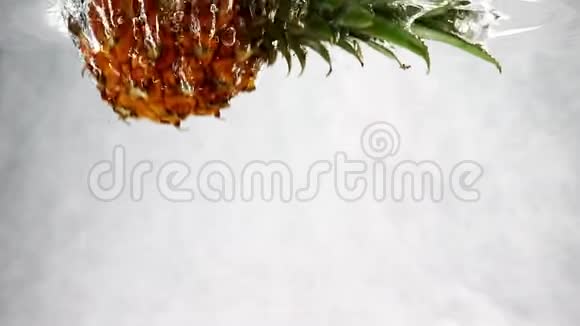 菠萝带着泡泡美丽地掉进水里慢动作的孤立白色背景菠萝视频的预览图
