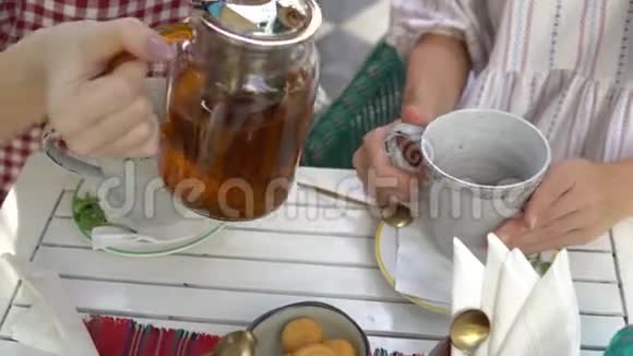 两个女人喝茶女人把茶从茶壶倒到杯子里视频的预览图