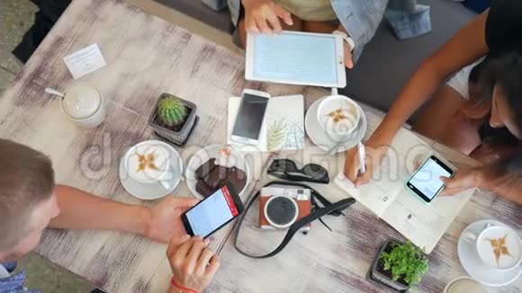 希普斯特朋友在咖啡店使用移动小工具高清慢动作生活方式特写双手和从上面看到的桌子视频的预览图