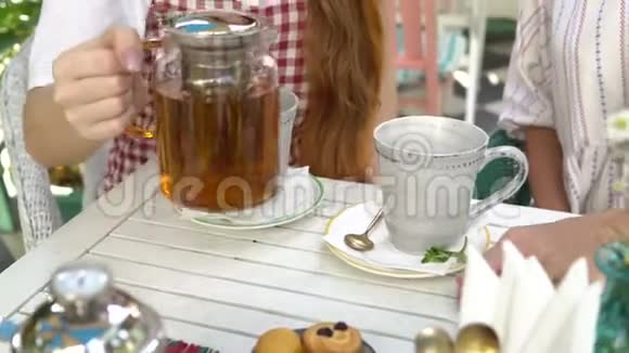 两个女人喝茶女人把茶从茶壶倒到杯子里视频的预览图