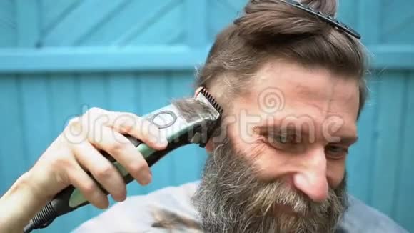 有胡子的奇怪男人试图用修剪器剪自己的头发视频的预览图