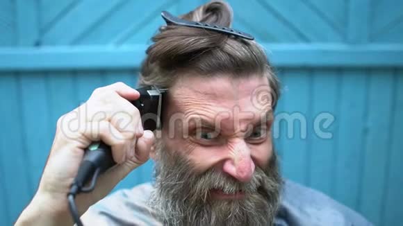 一个留着胡子想用剪刀剪头发的奇怪男人视频的预览图