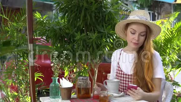 女人在户外喝茶的时候用手机视频的预览图