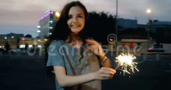 黄昏时分一位美丽的年轻女子在街上燃放烟花起舞视频的预览图