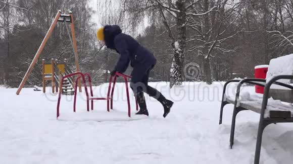年轻女子在冬季在儿童游乐场荡秋千4K视频的预览图