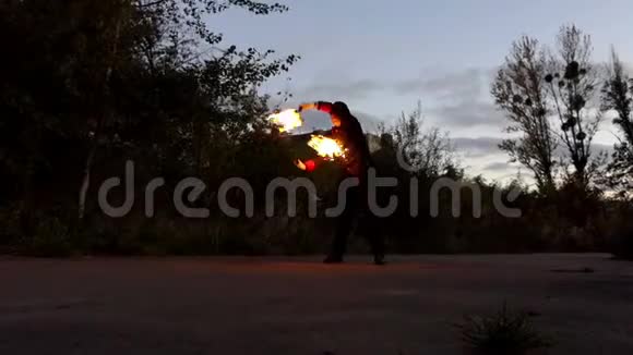 魔术师把两个燃烧的棍子绕在自己身边在斯隆莫看来很耀眼视频的预览图