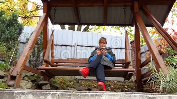 一个漂亮的女人在邋遢的院子里的一个荡秋千的长椅上游泳视频的预览图