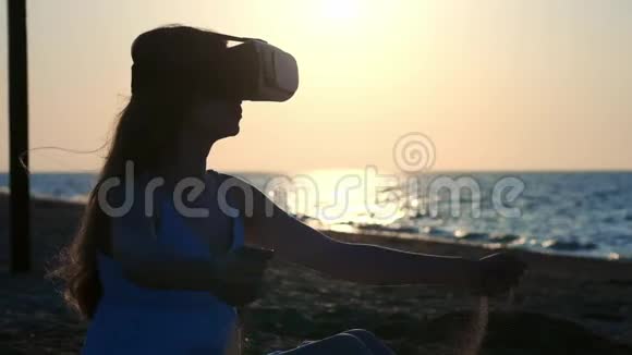 年轻女孩穿虚拟现实眼镜VR头饰把沙子从你的手指里倒出来在沙子上的位置视频的预览图