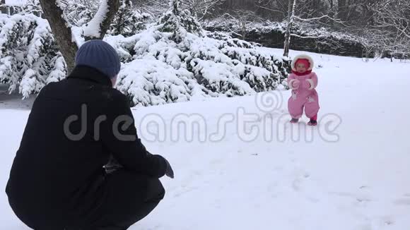 在寒冷的冬天爸爸和宝宝在雪地公园玩得很开心4K视频的预览图