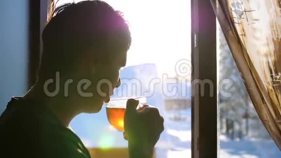冬天寒冷的一天那家伙一大早就站在窗口喝热茶视频的预览图