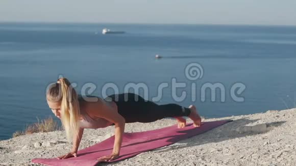 女人在山顶做瑜伽运动在背景上做海洋慢动作视频的预览图