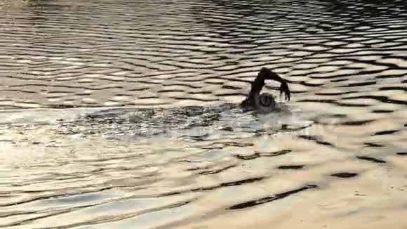 夏天的夜晚在斯隆莫的波光粼粼的河流中金发男子游着前爬行视频的预览图