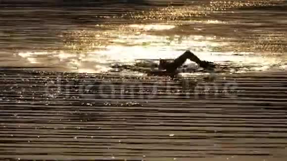 强壮的人在夏天的夜晚在波光粼粼的河流中游过前线视频的预览图