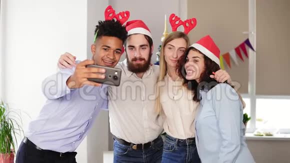 在办公室里戴着圣诞帽的快乐商人们正在自拍和微笑庆祝新年视频的预览图