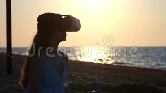 年轻女孩穿虚拟现实眼镜VR头饰把沙子从你的手指里倒出来在沙子上的位置视频的预览图
